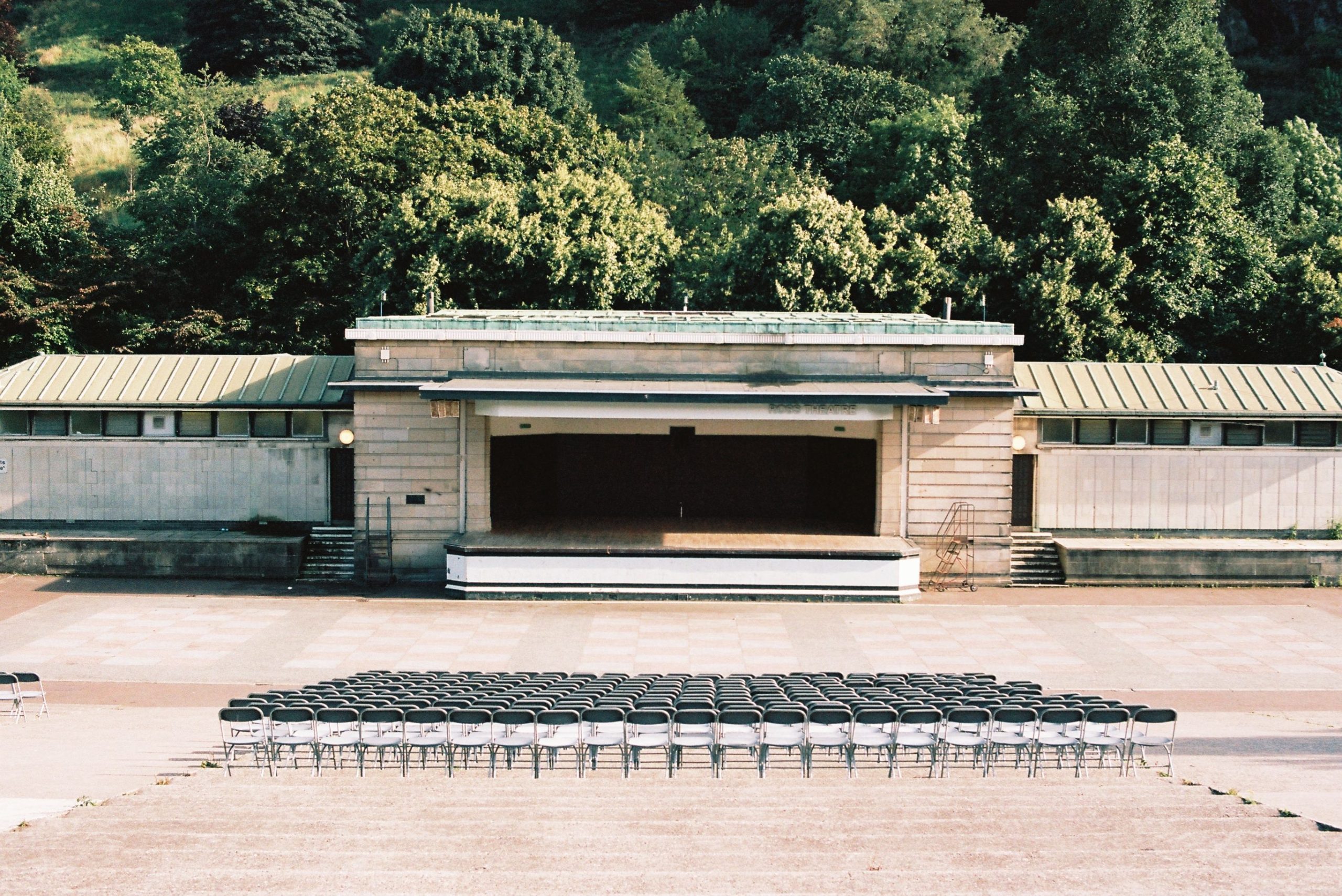 Outdoor concert stage with organized seating rows and lush greenery around the venue.